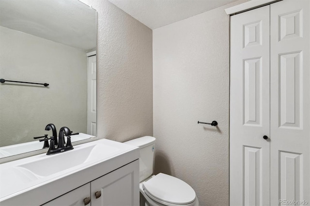 bathroom with vanity, toilet, and a textured ceiling