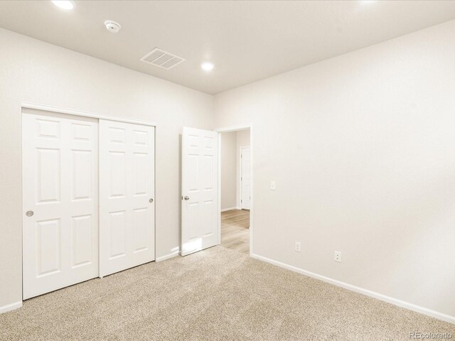 unfurnished bedroom with light carpet and a closet