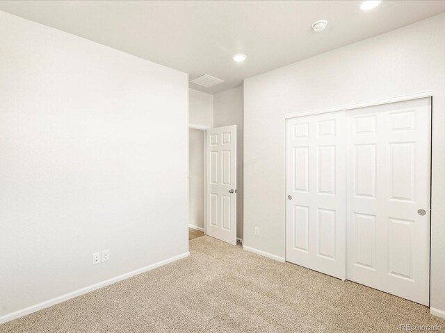 unfurnished bedroom with light colored carpet and a closet