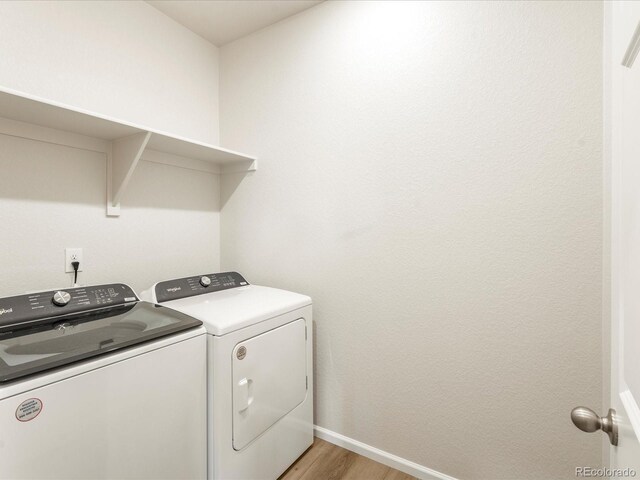 clothes washing area featuring washing machine and dryer and light hardwood / wood-style flooring