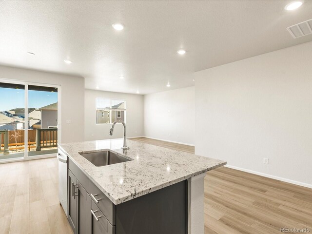 kitchen with dishwasher, an island with sink, light hardwood / wood-style flooring, and sink