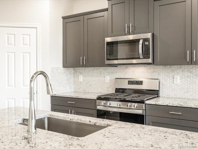 kitchen featuring decorative backsplash, light stone counters, and stainless steel appliances