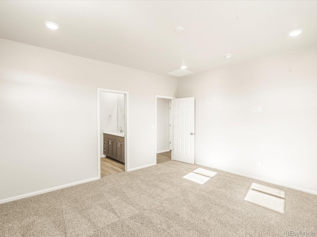 unfurnished bedroom featuring light carpet and connected bathroom