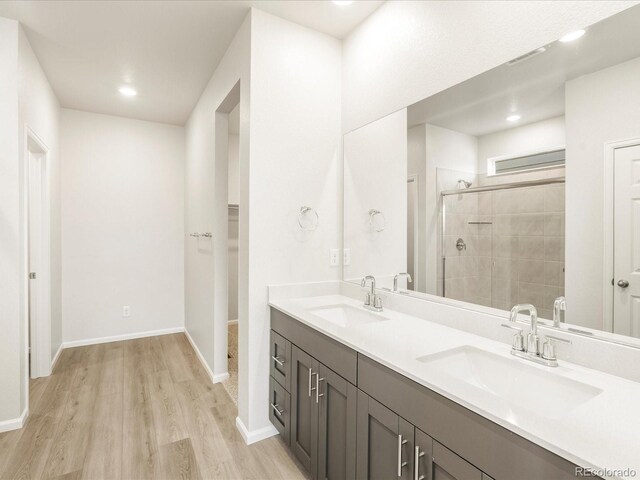 bathroom featuring a shower with door, vanity, and wood-type flooring