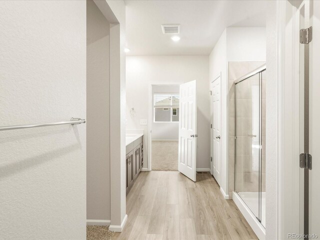 bathroom featuring a shower with door, vanity, and wood-type flooring