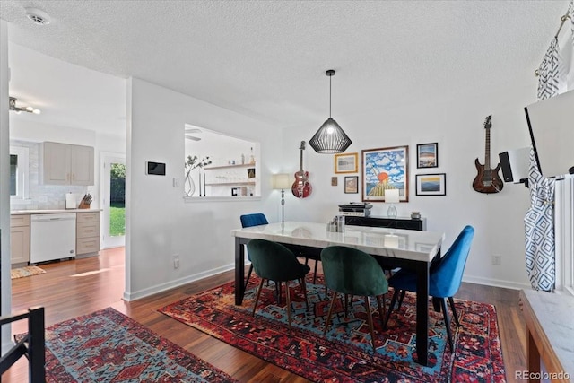 dining space featuring a textured ceiling, wood finished floors, and baseboards
