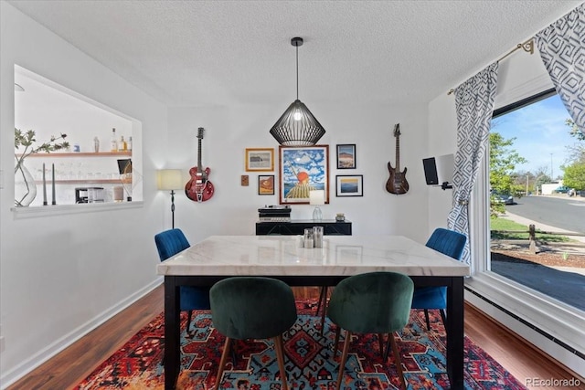 dining space with baseboard heating, a textured ceiling, dark wood-type flooring, and baseboards