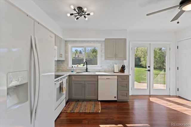 kitchen featuring white appliances, gray cabinets, a sink, and plenty of natural light