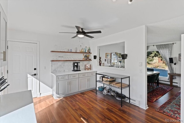indoor bar featuring dark wood-style flooring, a ceiling fan, and a baseboard heating unit