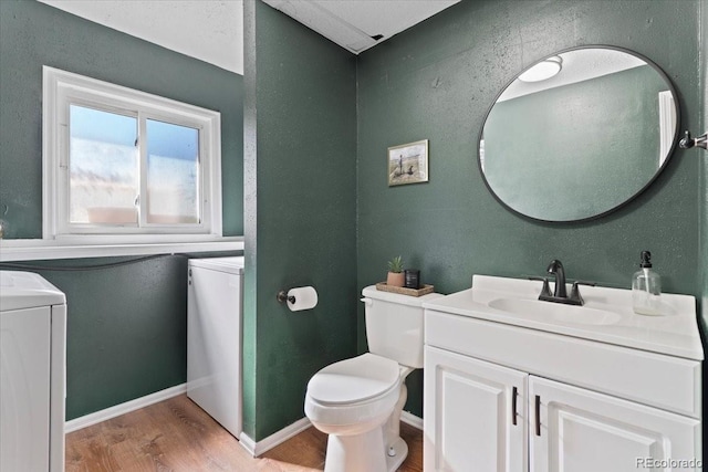 half bathroom featuring washer / clothes dryer, toilet, wood finished floors, and vanity