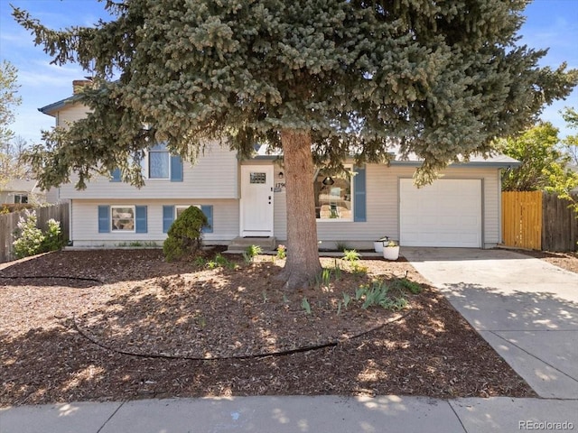 view of front of home with an attached garage, concrete driveway, and fence