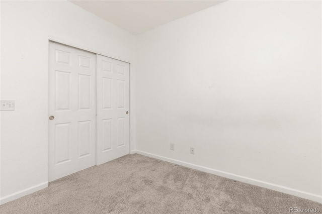 unfurnished bedroom with light colored carpet and a closet