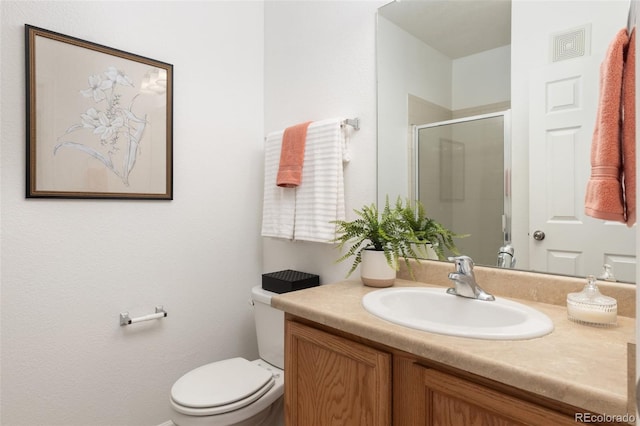 bathroom featuring vanity, toilet, and a shower with door