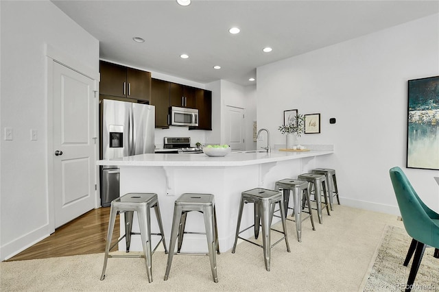 8458 Parkland St, Broomfield, CO 80021 - kitchen featuring stainless steel appliances, a breakfast bar, a peninsula, recessed lighting, and light countertops