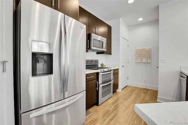 8458 Parkland St, Broomfield, CO 80021 - kitchen featuring appliances with stainless steel finishes, light wood-style flooring, dark brown cabinetry, light countertops, and recessed lighting