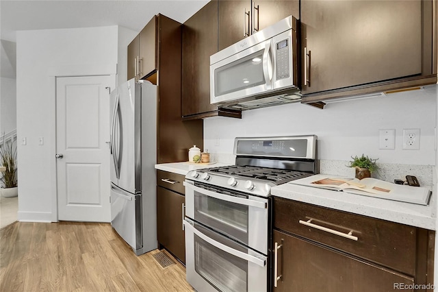 8458 Parkland St, Broomfield, CO 80021 - kitchen with appliances with stainless steel finishes, dark brown cabinets, light wood-style floors, and light countertops
