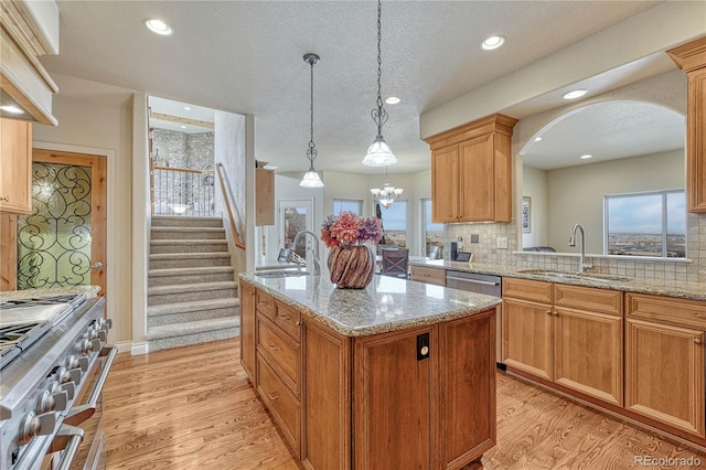 kitchen featuring a textured ceiling, sink, an island with sink, and stainless steel appliances