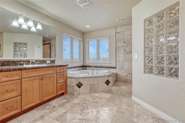 bathroom featuring vanity, a textured ceiling, and tiled tub