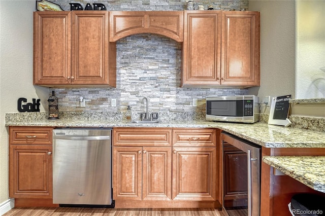 kitchen with wine cooler, appliances with stainless steel finishes, light stone countertops, sink, and light hardwood / wood-style flooring