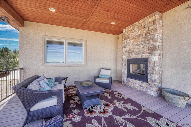 wooden terrace featuring an outdoor stone fireplace