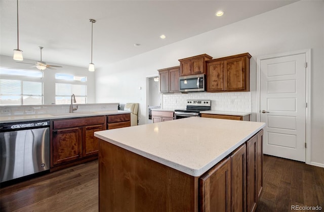 kitchen featuring sink, appliances with stainless steel finishes, a center island, decorative backsplash, and decorative light fixtures