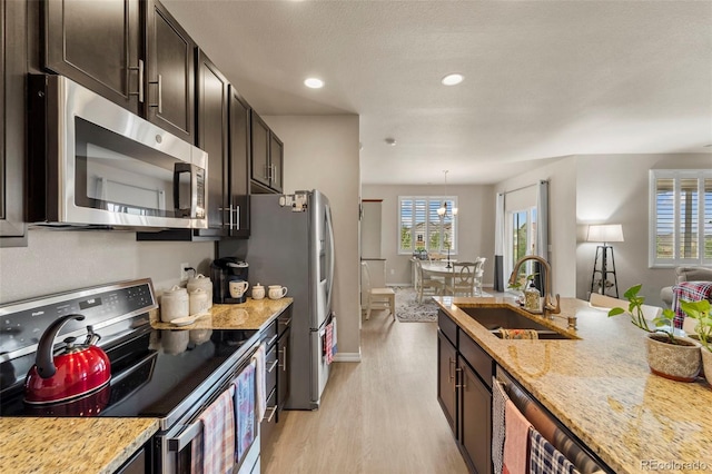 13138 Stoney Meadows Way, Peyton, CO 80831 - kitchen featuring appliances with stainless steel finishes, light wood-type flooring, light stone counters, dark brown cabinets, and recessed lighting