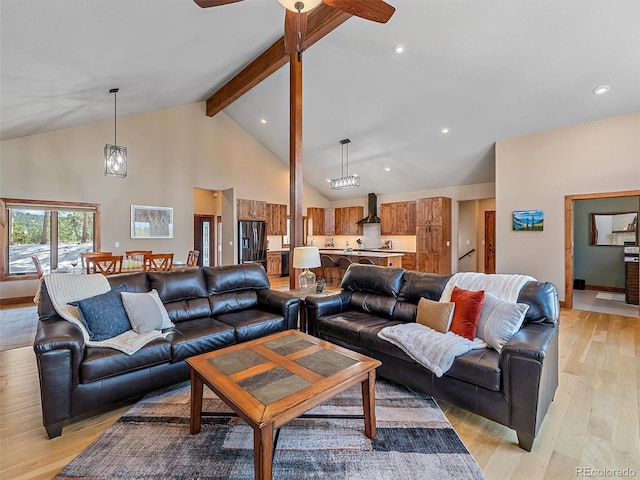 living area featuring beam ceiling, high vaulted ceiling, ceiling fan, and light wood finished floors