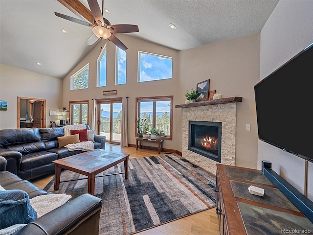 living area featuring a ceiling fan, light wood-style floors, a healthy amount of sunlight, and a fireplace