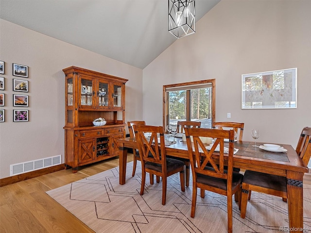 dining area featuring visible vents, high vaulted ceiling, light wood-type flooring, and baseboards