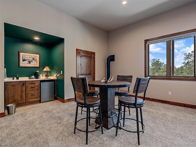 dining room featuring recessed lighting, light colored carpet, wet bar, and baseboards