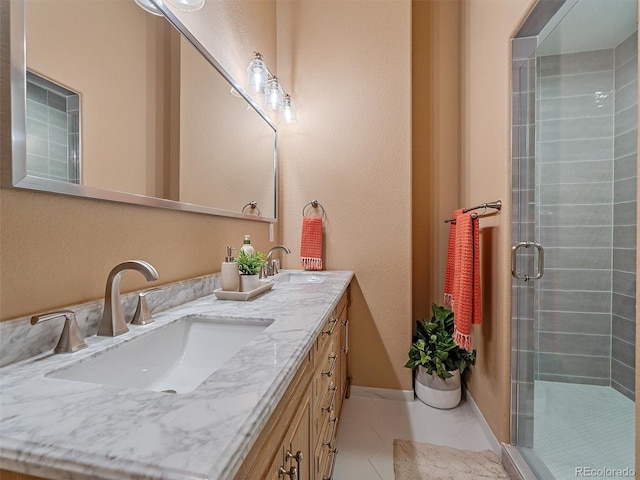 full bathroom with double vanity, tile patterned flooring, a stall shower, and a sink