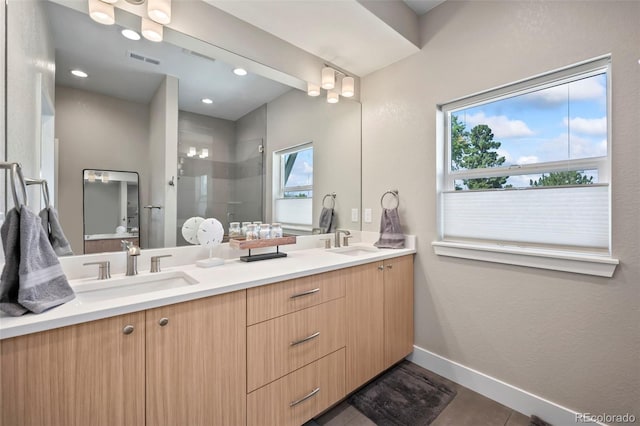 full bathroom with a sink, a shower stall, visible vents, and baseboards