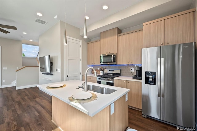 kitchen with dark wood-type flooring, sink, stainless steel appliances, a kitchen island with sink, and decorative backsplash