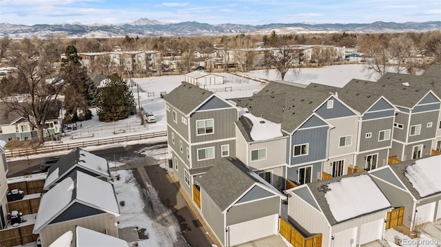 snowy aerial view with a mountain view and a residential view