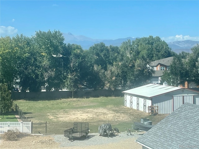 view of yard with fence, a mountain view, and an outdoor structure