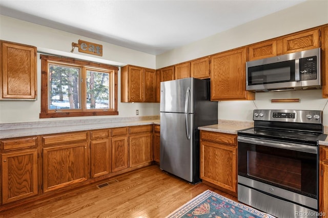 kitchen with appliances with stainless steel finishes and light hardwood / wood-style flooring