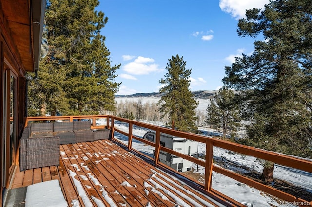 snow covered deck featuring a mountain view and outdoor lounge area