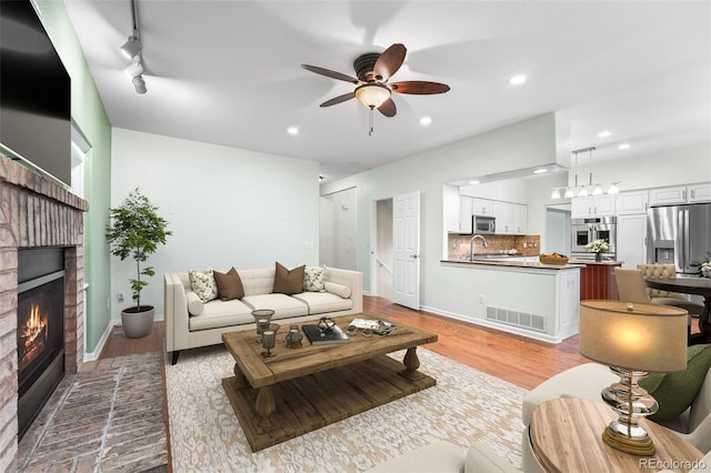 9365 Erminedale Dr, Lone Tree, CO 80124 - living area with a brick fireplace, ceiling fan, recessed lighting, and light wood-type flooring