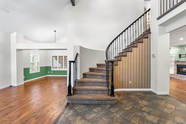 9365 Erminedale Dr, Lone Tree, CO 80124 - stairs featuring high vaulted ceiling, a brick fireplace, and wood finished floors