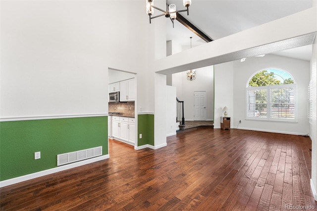 9365 Erminedale Dr, Lone Tree, CO 80124 - unfurnished living room featuring a chandelier, vaulted ceiling, dark wood-style flooring, and stairs