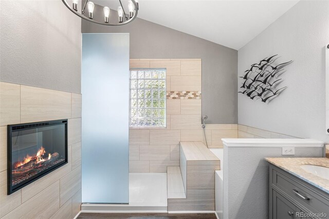 9365 Erminedale Dr, Lone Tree, CO 80124 - full bath with vaulted ceiling, vanity, a tile shower, a fireplace, and a chandelier
