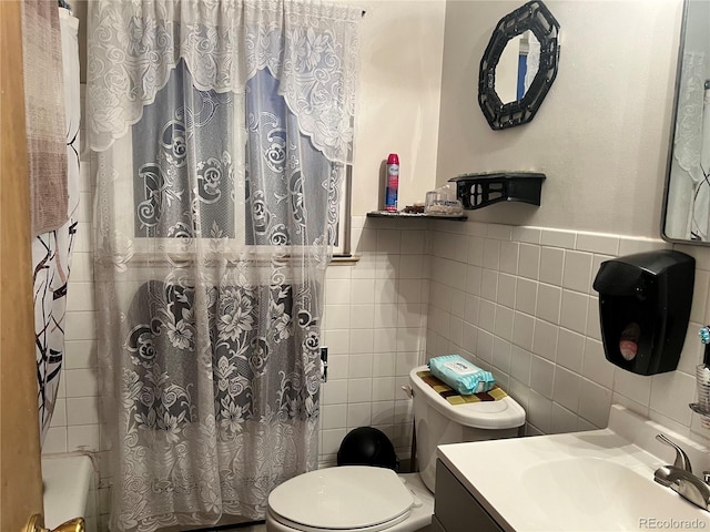 bathroom with vanity, toilet, and tile walls