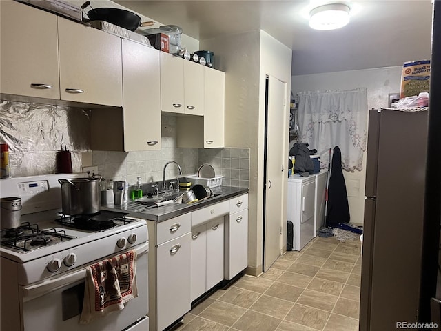 kitchen with washing machine and dryer, white gas stove, white cabinets, and fridge