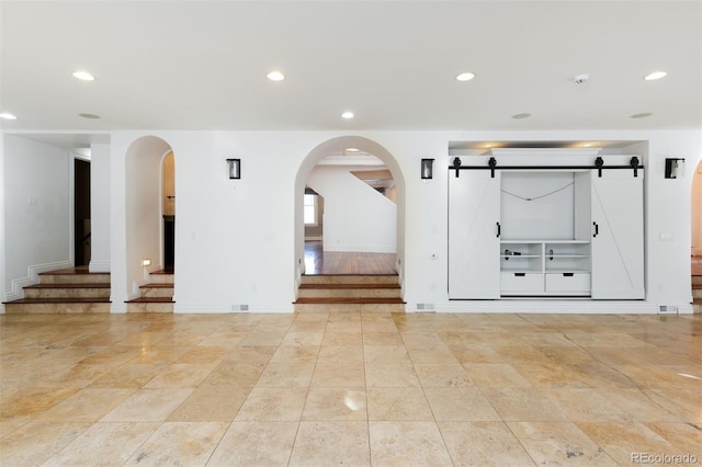 empty room with a barn door and light tile patterned flooring