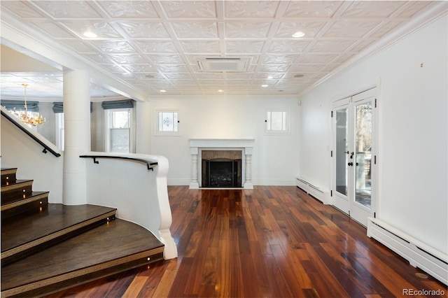 living room featuring an inviting chandelier, a baseboard heating unit, crown molding, and dark wood-type flooring