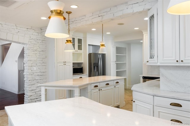 kitchen featuring stainless steel appliances, a center island, hanging light fixtures, and white cabinets