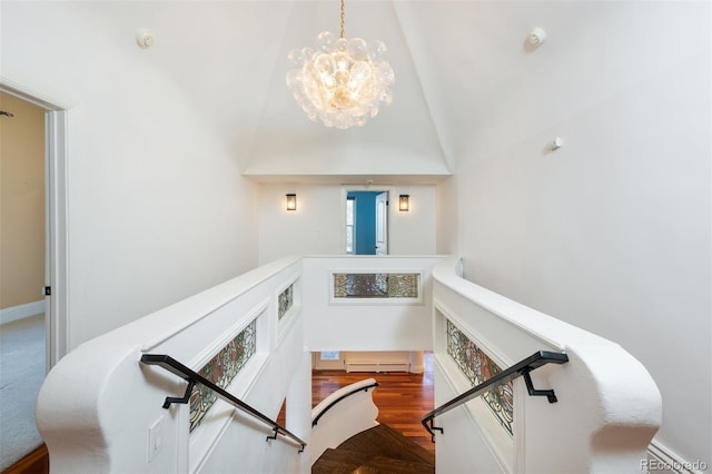 stairs with a baseboard radiator, a chandelier, and hardwood / wood-style floors