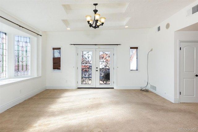 empty room with french doors, light colored carpet, a notable chandelier, and a wealth of natural light