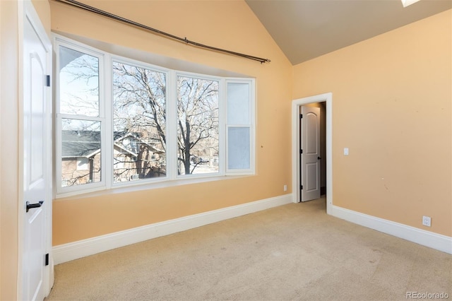 spare room featuring light colored carpet and lofted ceiling