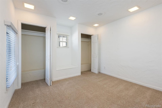 unfurnished bedroom with light carpet and two closets